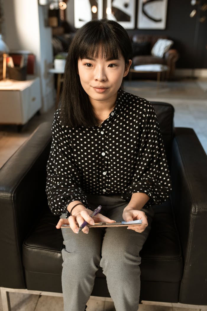 Asian woman sitting in an office setting, preparing for a job interview with a tablet in hand.